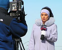Un reportero de televisión sosteniendo un micrófono.