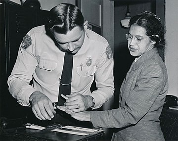 Rosa Parks is arrested for refusing to sit behind a white person on a bus (1955)