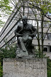 Monumento a Sigmund Freud en Hampstead, al norte de Londres. Sigmund y su hija Anna Freud vivieron en el número 20 de Maresfield Gardens, cerca de esta estatua. Su casa es ahora un museo dedicado a la vida y obra de Freud. El edificio que se encuentra detrás de la estatua es la Clínica Tavistock, una importante institución de atención psicológica.  