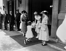 Overrækker blomster til dronningen uden for Brisbane City Hall, 1954. Dette er en "bob"-knæfald, som bruges af unge piger og af tjenestepiger i store huse.