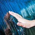 Photo of flowing water adhering to a hand. Surface tension creates the sheet of water between the flow and the hand.