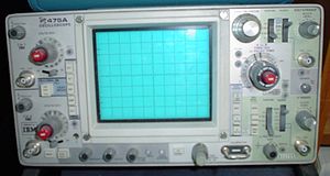 Ein tragbares Analog-Oszilloskop Modell 475A von Tektronix, typisch für die späten 1970er Jahre. Dieses Dual-Trace-, Dual-Sweep-Instrument hatte eine horizontale Bandbreite von 250 MHz, eine maximale vertikale Empfindlichkeit von 5 mV pro Teilung und eine maximale (nicht vergrößerte) horizontale Sweep-Geschwindigkeit von 10 ns pro Teilung. Die vertikalen Bedienelemente befinden sich auf der linken Seite, Kanal 1 oben und Kanal 2 unten. Die Bedienelemente für den horizontalen Sweep befinden sich auf der rechten Seite, wobei der Haupttrigger oben und der verzögerte Trigger unten ist. Die CRT-Steuerungen befinden sich unterhalb des Bildschirms. Die Metallschleife unten rechts auf dem Bildschirm liefert ein Kalibriersignal für Spannungs- und Stromsonden.