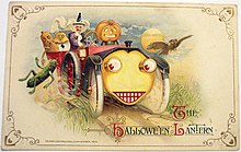"Halloween-lygten". Postkort fra 1914, der viser en heks og antropomorfe frugter og grøntsager i en bil med et menneskeligt ansigt på køleren foran.  
