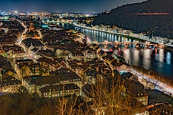 Opposite view from the castle park to the old town with the Heiliggeistkirche and the old bridge over the Neckar to the Philosophenweg, recognizable by the traces of a vehicle.